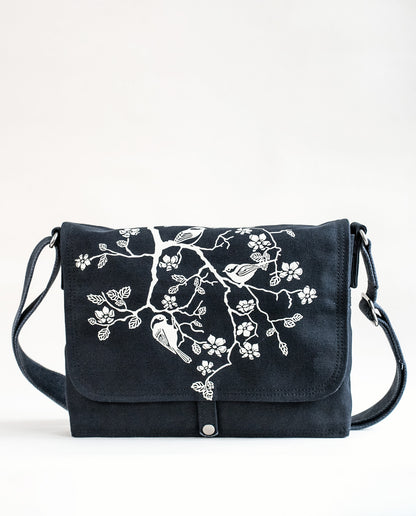 Front exterior of Dock 5’s Chickadee Canvas Messenger Bag in black featuring art from owner Natalija Walbridge