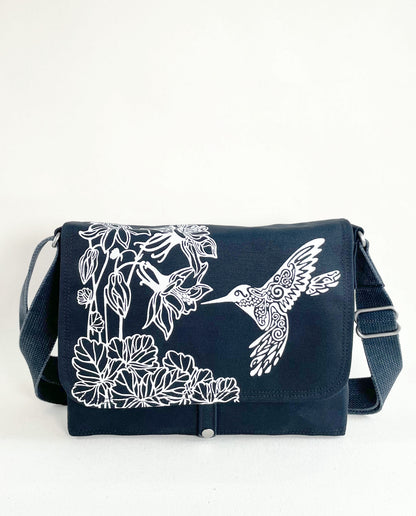 Front exterior of Dock 5’s Hummingbird Canvas Messenger Bag in black featuring art from owner Natalija Walbridge