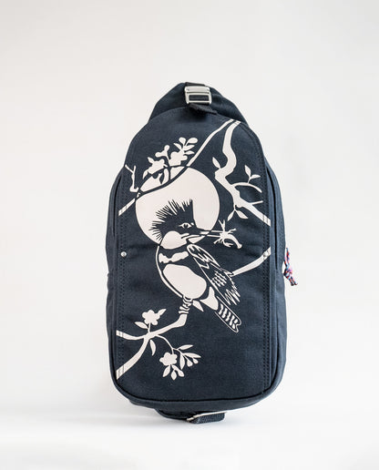 Front exterior of Dock 5’s Kingfisher Canvas Sling Bag in black featuring art from owner Natalija Walbridge