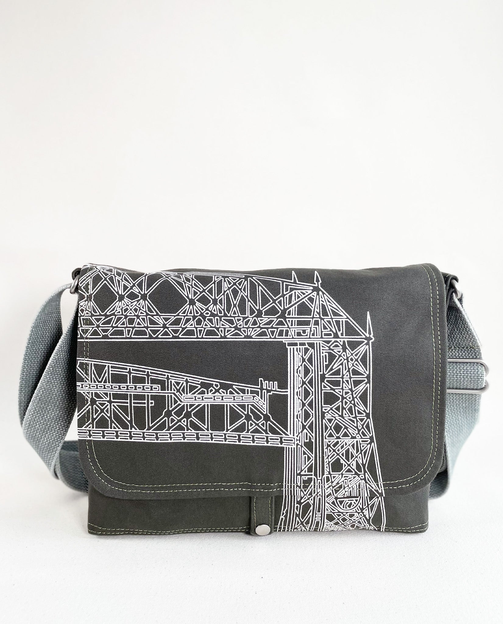 Front exterior of Dock 5’s Lift Bridge Canvas Messenger Bag in olive featuring art from owner Natalija Walbridge