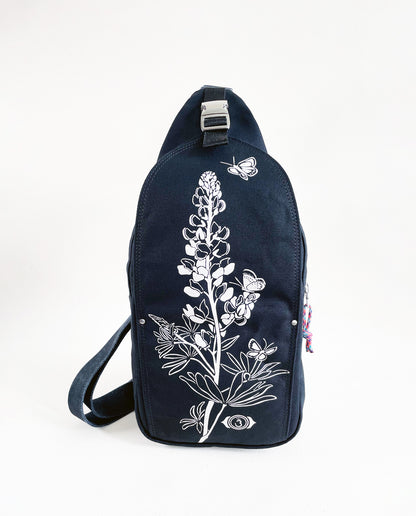 Front exterior of Dock 5’s Lupine Canvas Sling Bag in black featuring art from owner Natalija Walbridge