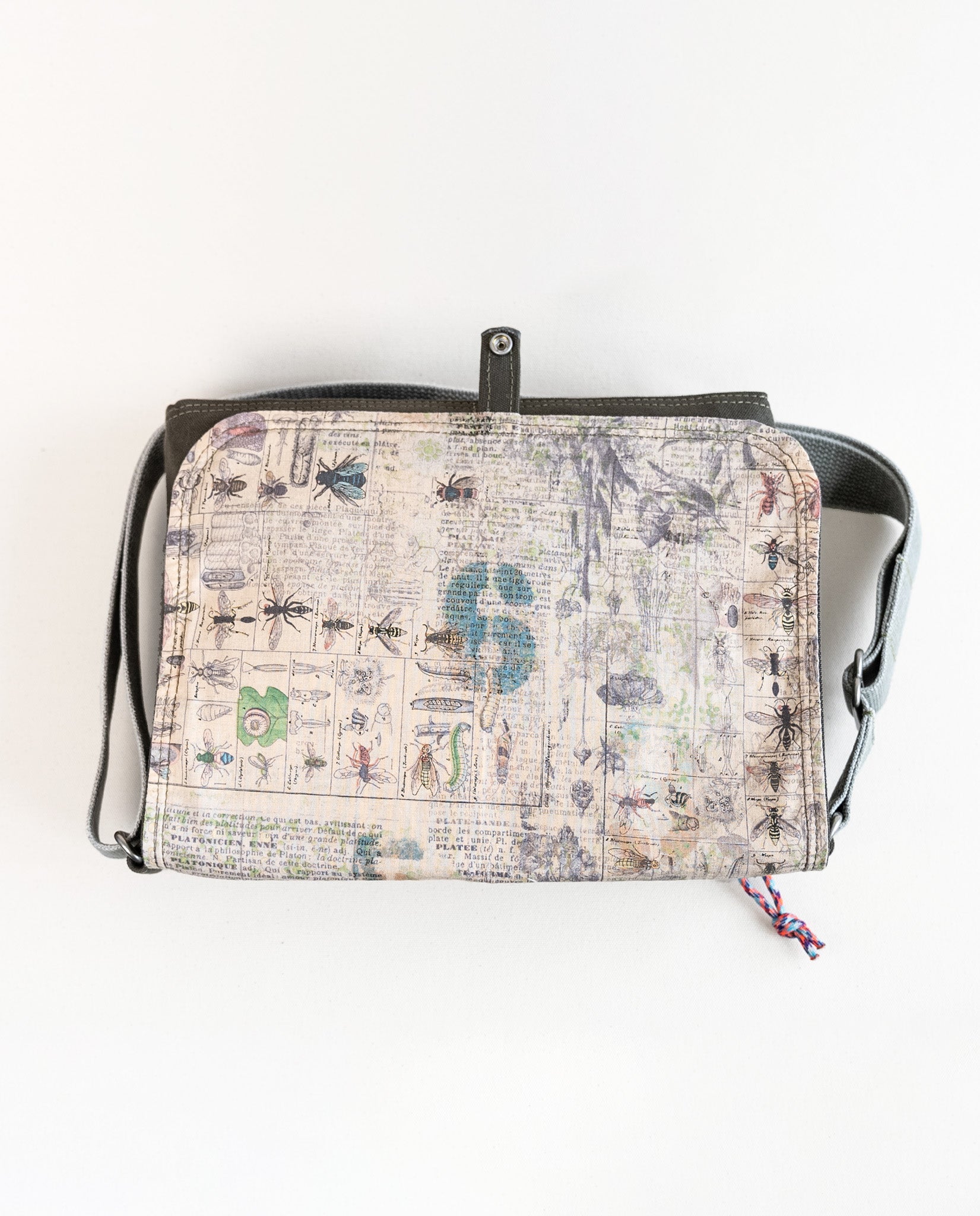 Inside of flap showing entomology print lining fabric of Dock 5’s Chickadee Canvas Messenger Bag in olive featuring art from owner Natalija Walbridge