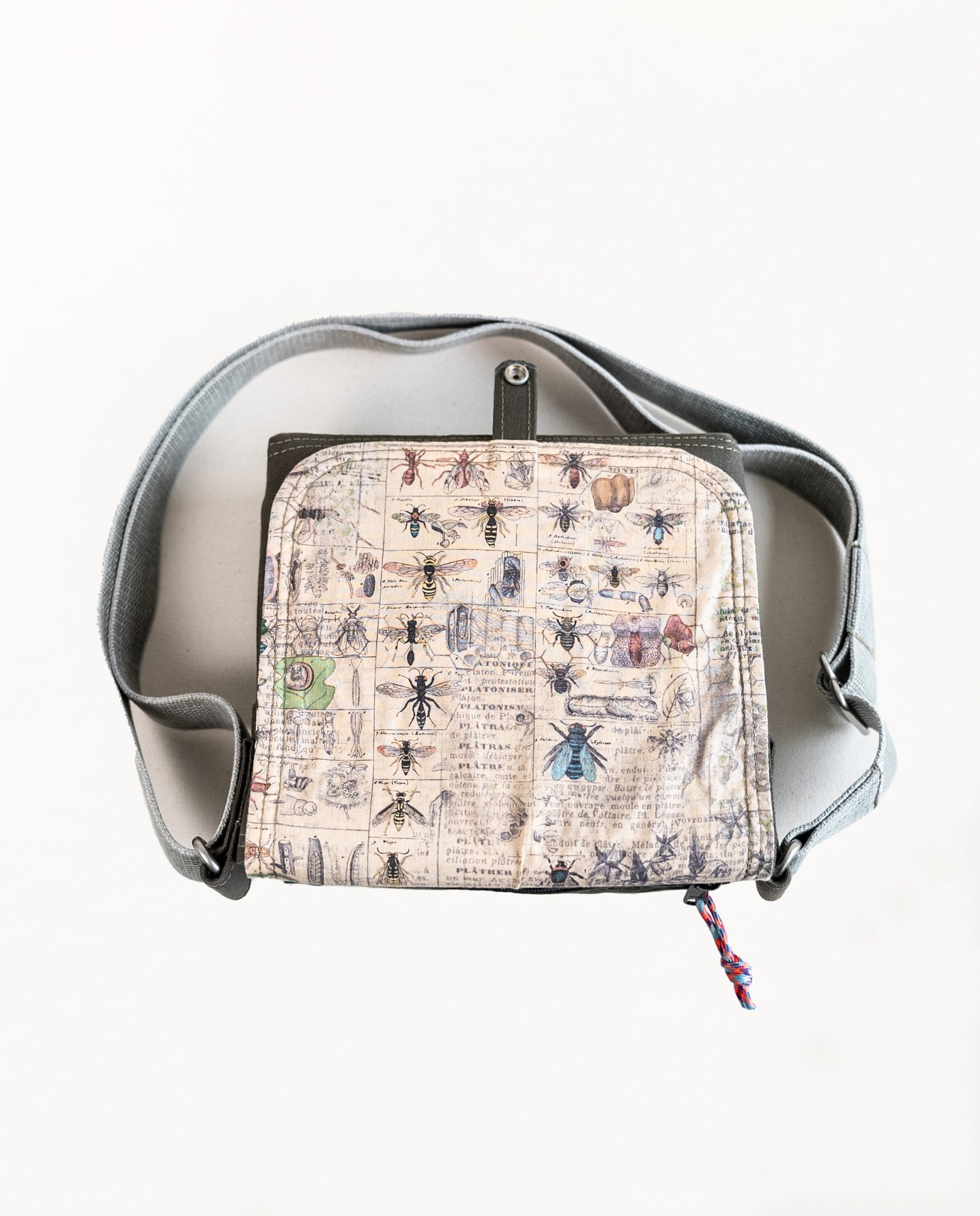 Inside of flap showing entomology print lining fabric of Dock 5’s Chickadee Canvas Mini Messenger Bag in olive featuring art from owner Natalija Walbridge