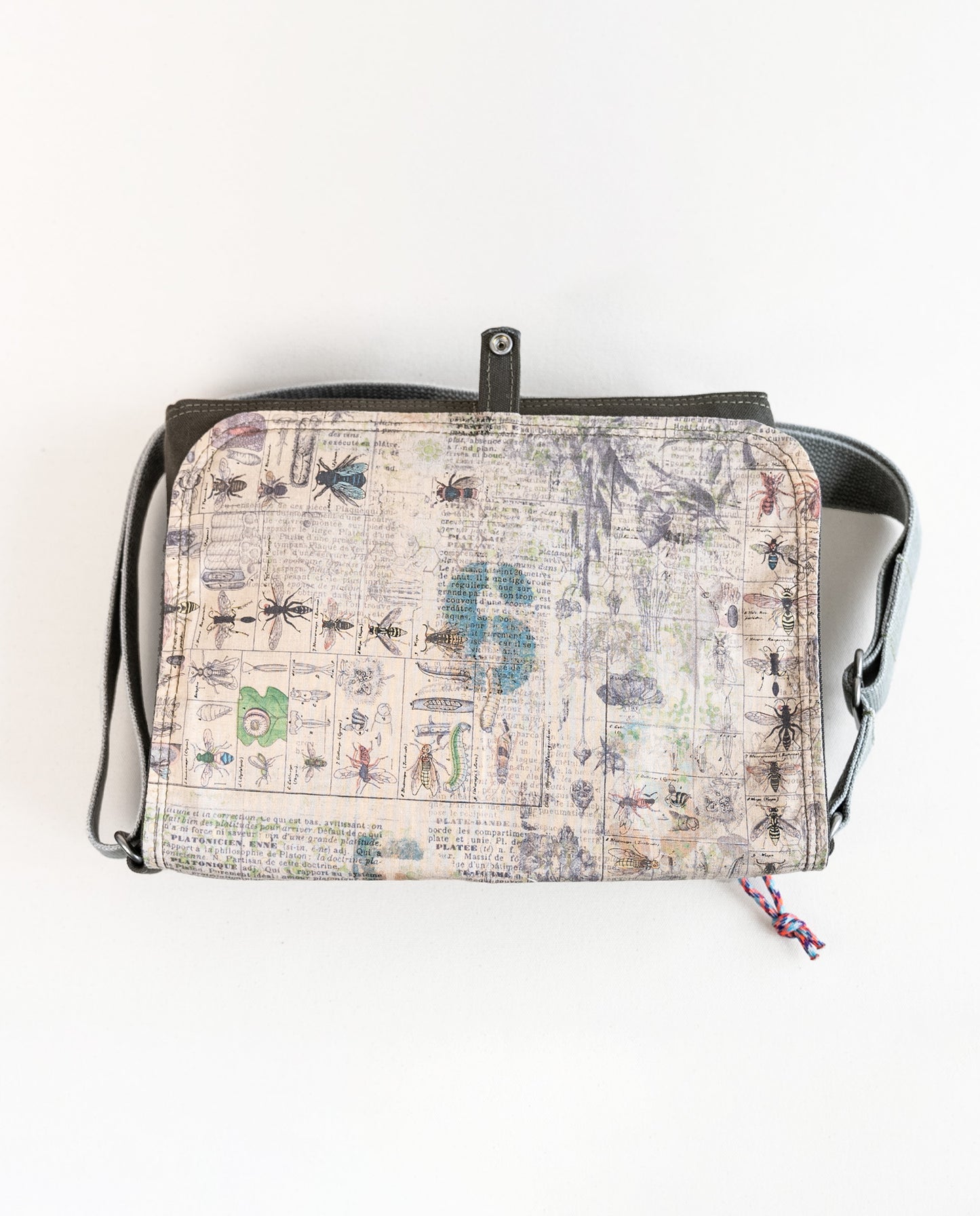 Inside of flap showing entomology print lining fabric of Dock 5’s Snowy Owl Canvas Messenger Bag in olive featuring art from owner Natalija Walbridge